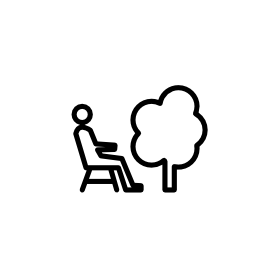 ツリーの無料アイコンの横にいすに座る人