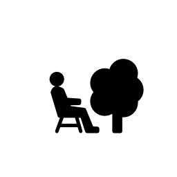 ツリーの無料アイコンの横にいすに座る人